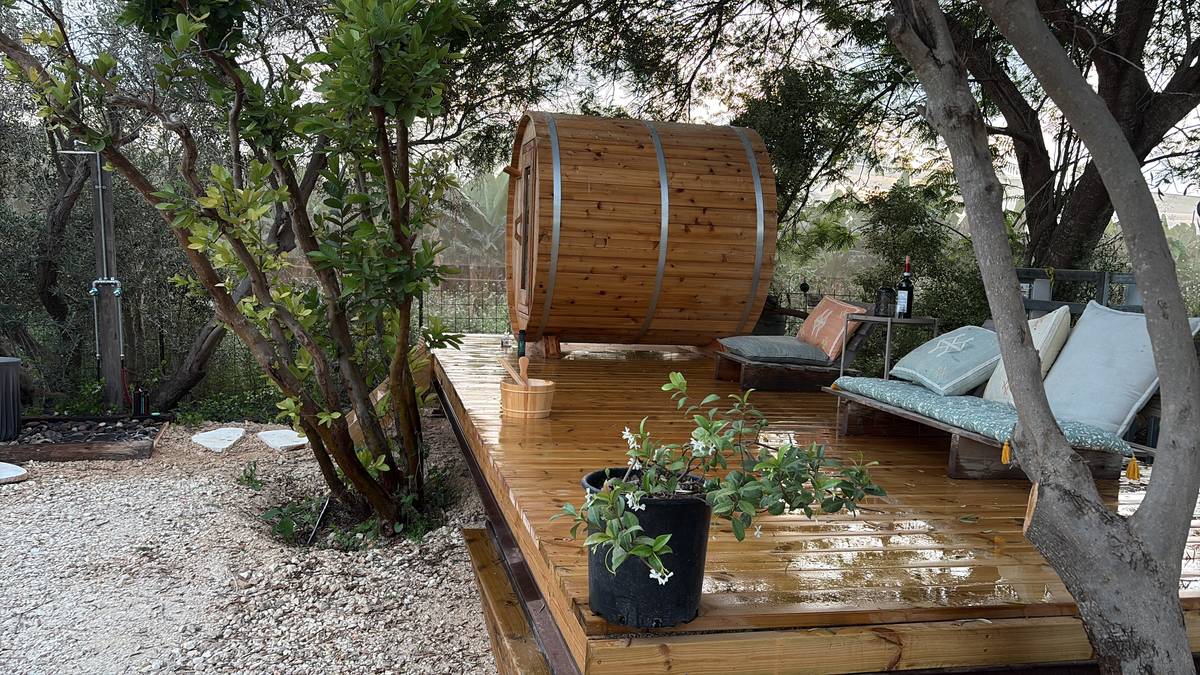 Wet wooden spa deck with barrel sauna and cushioned loungers